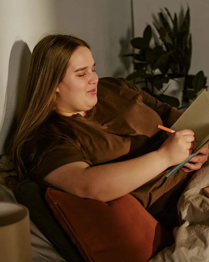 A woman writes in her journal in bed at night